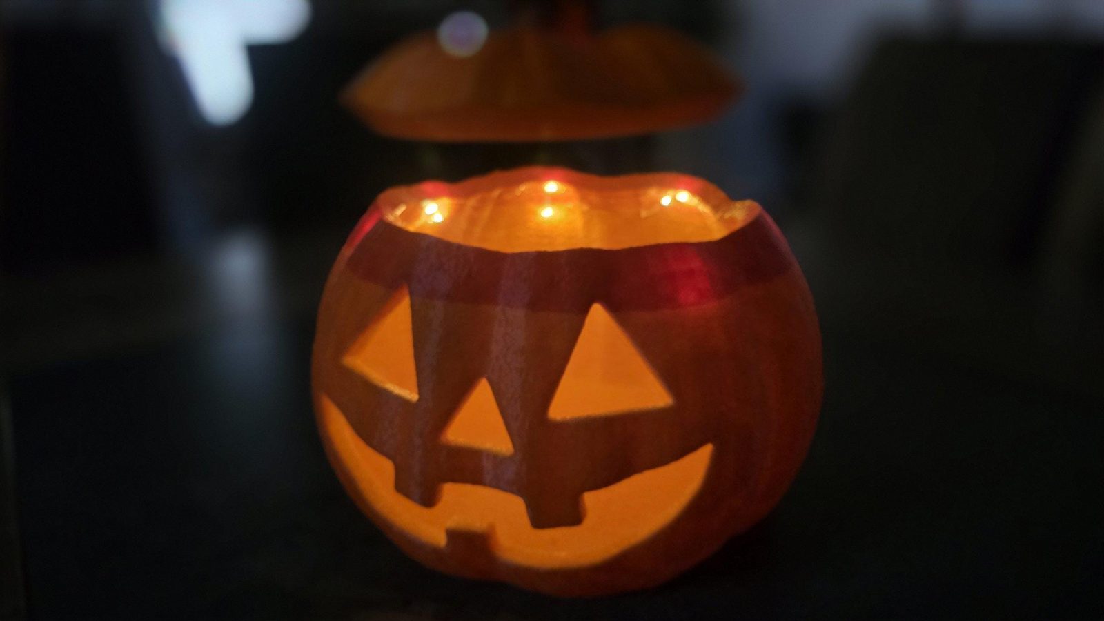 Citrouille ouverte, couvercle retiré au-dessus, guirlande LED allumée visible à l'intérieur